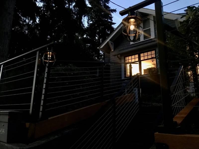 House at dusk with a sunset reflection in its window, flanked by two glowing modern