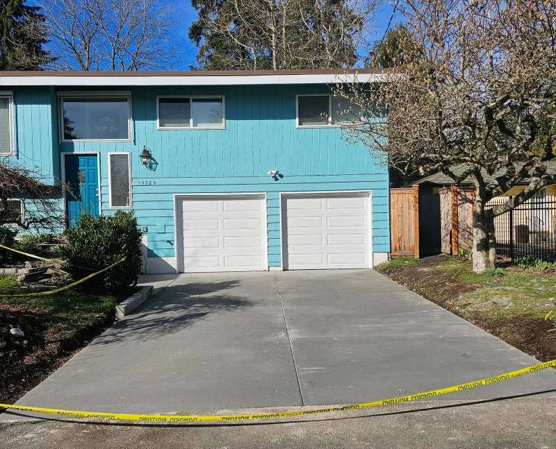 Teal house with two white garage doors