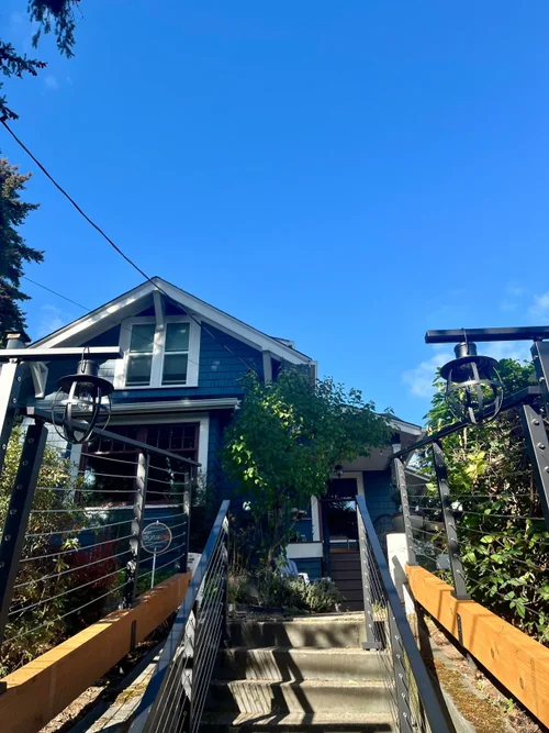 Exterior staircase with black railing leading to a renovated home entrance