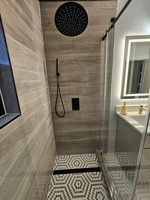 Custom tiled shower with black fixtures and decorative floor tile
